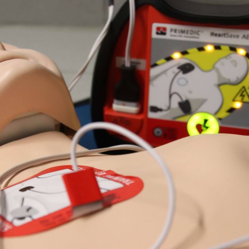 Ein Defibrilator ist an einer Übungspuppe angeschlossen
