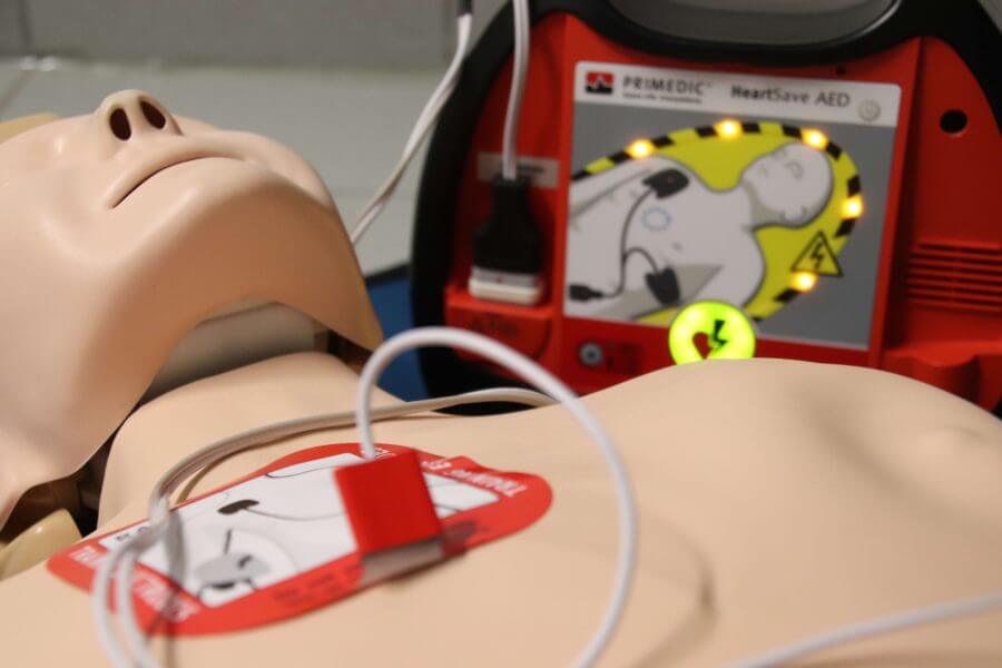 Ein Defibrilator ist an einer Übungspuppe angeschlossen